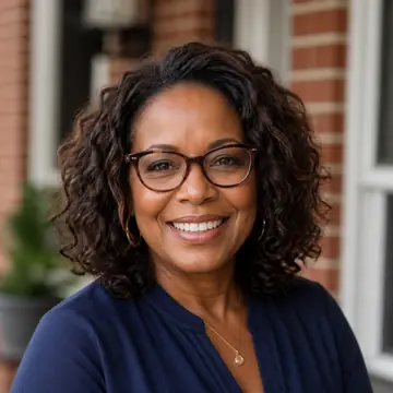 A smiling Black woman local investor stands outside a residential brick home.